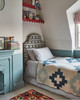 Children's bedroom featuring a single bed with Papas headboard and toys on red shelves. Design by Polly Asham